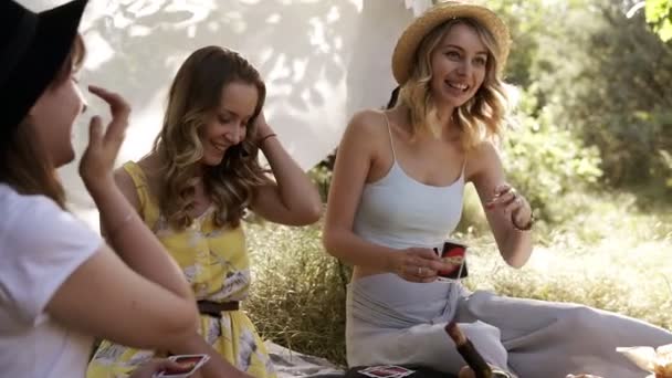 一群女孩朋友在户外做野餐。他们坐着, 微笑着, playng 纸牌游戏。母鸡党的概念。夏天 — 图库视频影像