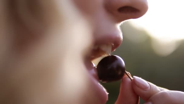 Primo piano ritratto di belle donne faccia mangiare una ciliegia. Mira al filmato di una bocca femminile. All'aperto — Video Stock