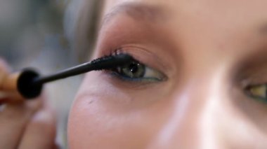 Son derece bir genç kadının gözü kapatın. Dikkatle siyah rimel uygulamak sanatçı olun. Yeşil gözlü beyaz modeli