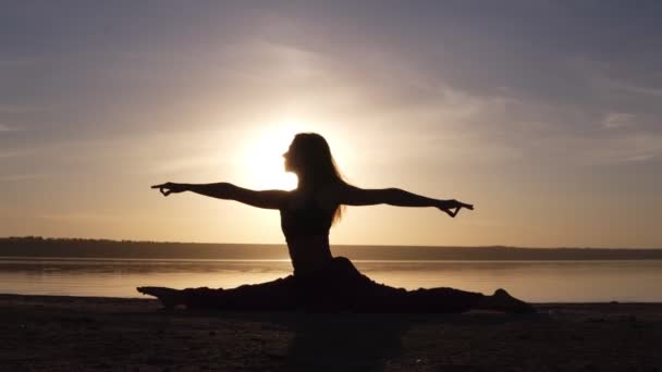Hermosa silueta de mujer haciendo yoga, dividida en la costa del mar. Mañana amanece, sol de smog en el backstage thee — Vídeos de Stock