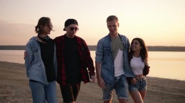 Arkadaşlarım ile hayattan zevk. Sahilde birlikte akşam alacakaranlıkta yürüyen iki güzel genç çiftler. Erkek arkadaşlarını sarılıyorlar. Gülümseyen