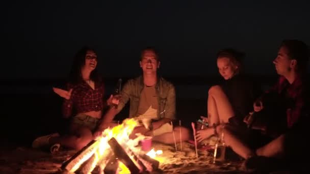 Grupo de amigos pasando el rato juntos en la playa. Hermosas dos parejas. Cantando canción con guitarra, haciendo gestos. Concepto de amistad. Hoguera en la noche — Vídeos de Stock