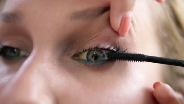 De Visagist liften van het ooglid van het model en vlekken van wimpers met mascara stok. Zwarte kleur. Close-up — Stockvideo