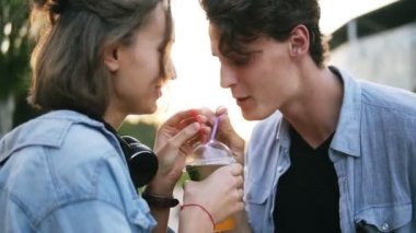 Park ayakta çekici genç çift portre görünümünü ve ve birlikte iki kamış kullanarak içme milkshake paylaşımı