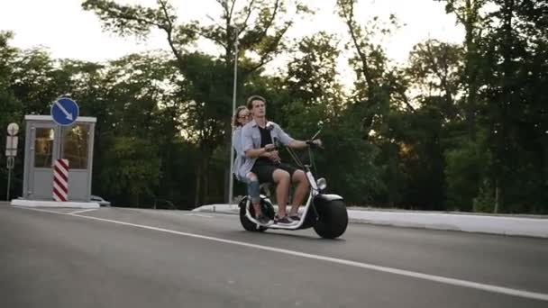 Vue latérale d'un couple à vélo et s'amuser. Belle jeune femme et homme conduisant autour de la ville. Liberté, mode de vie heureux — Video