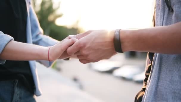 Крупним планом кадри молодої пари тримає руки, що зустрічаються в парку. Хлопець пестить дівчат за руку — стокове відео