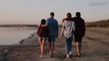 Sahilde yürüyüş bir beyaz gençler görüntülerini araştırıyorum. İki çiftler bir kucaklama gidin. Arka görünüm