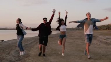 Mutlu birlikte sahilde çalışan arkadaş grubu. Özgürlük, sevinç ve mutluluk. Ellerini gökyüzüne yetiştirme