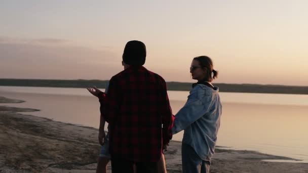 Des amis passent du temps ensemble au bord de la mer. Parler, sourire, discuter de quelque chose. La culture des jeunes. Bonsoir. — Video