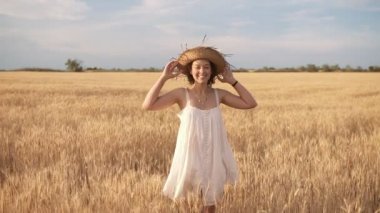 Güzel esmer kıvırcık Bayan yaz buğday alanında. Gülümseyen ve hasır şapka poz. Önden görünüm