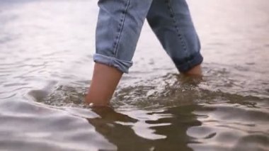 Su, mavi kot pantolon gölde yürüyen bir genç kadının ayakları görüntülerini kapatın. Gündüz, yaz