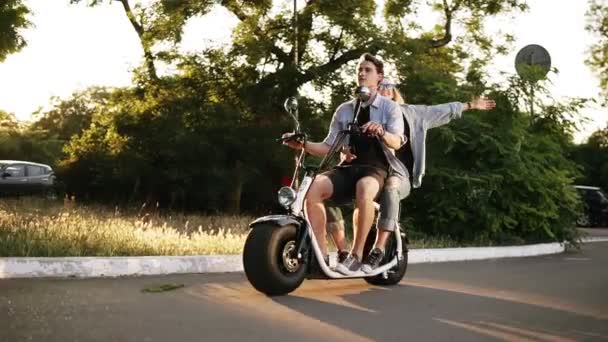 Ein glückliches Paar, das an einem Sommertag auf einem Elektro-Fahrrad in der Straße unterwegs ist. schöne Mädchen und ihr Freund genießen ihre Zeit. Parkgebiet — Stockvideo