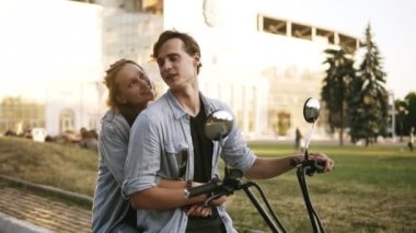 Bir bisiklet üzerinde oturan bir beatuful Çift görüntüleri genel bakış. Kız adam arkadan sarılıyor. Siyah T gömlek ve mavi tişört giyiyor. Yaz günü