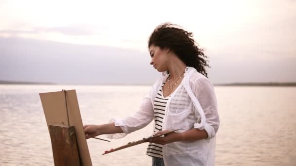 アーティストの作業のクローズ アップ。イーゼルと彼女の手でパレットを保持します。美しい周囲の風景: ミラー湖と空をクリア — ストック動画