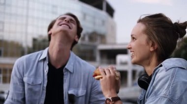 Mutlu bir genç çift parkta takılıyorsun. Gülüyorsun ve gülümseyerek. Kız Hamburger yiyor. Genç adam yavaşça sos kızlar dudaklarını mendil ve parmağını yalıyor. Yakın çekim