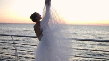 Bir çubuk eğilerek ve germe uzun beyaz tutu güzel balerin. Bacağını dikey bir sicim bükme. Sabah alacakaranlıkta. Seaside