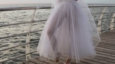 Kol demiri açık havada duran bir güzel balerin duygusal sahne. Beyaz tutu ve pointe genç womaan. Seaside, sabah