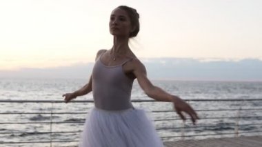 Genç, ince bir balerin portresi beyaz tutu tek ayak üzerinde dönüş pratik giyinmiş. Zarif kadın açık havada egzersiz. Sabah alacakaranlıkta