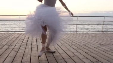 Genç balerinler dans hareket bacaklarda görüntülerini kapatın. Uzun beyaz tutu ve açık havada, ahşap zemin egzersiz pointe balet. Gündüz