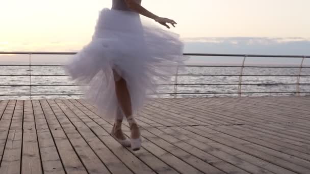 バレリーナの足の映像を閉じます。彼女は彼女のトウシューズ バレエの踊り。シーズは白いチュチュ ドレスを着ています。つま先でぐるぐる回る。スローモーションで — ストック動画