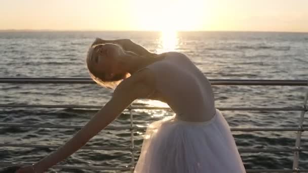 Beautiful scene of dancing ballerina in white tutu near ocean or sea in morning. Beautiful woman practicing hands exercises. Flare — Stock Video