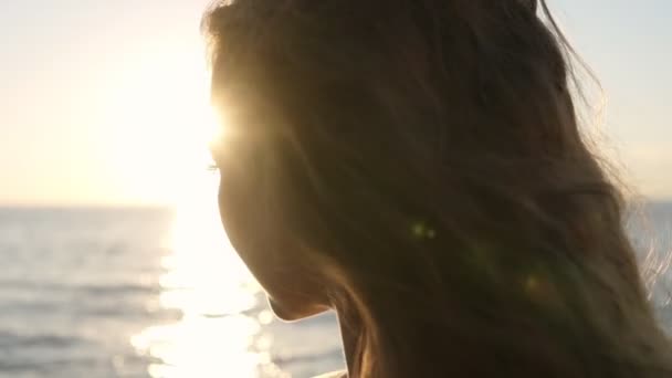 Beautiful portrait of a young brunette woman standing facing to the sunlight. Looking thoughtfully, enjoying the summer and freshness of the air — Stock Video
