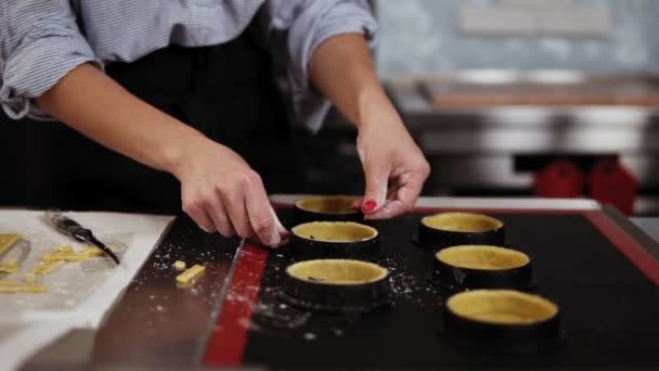 Gros plan des mains de femmes avec la modélisation de manucure rouge et la préparation de pâte à biscuits pour la cuisson à l'aide de petits moules de cuisson. Surface de travail, atelier culinaire — Video