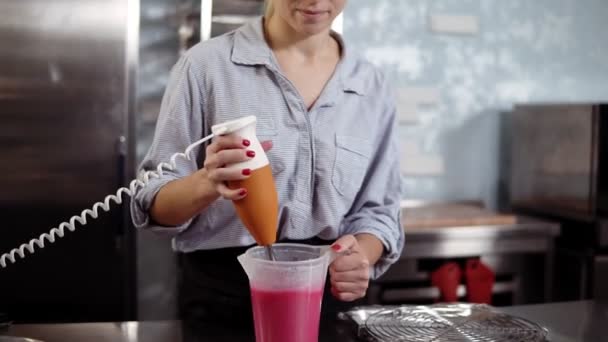 Proces van de voorbereiding van roze mirror glaze. Vooraanzicht van een vrouw banketbakker ingridients voor glazuur met behulp van een mixer mengen. Moderne keuken — Stockvideo