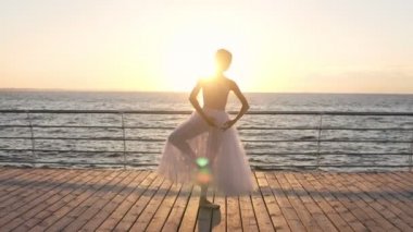 Egzersiz, açık havada denize yakın ahşap zemin üzerinde duran germe muhteşem beyaz balerin. Kadın sicim. Sabah