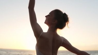 Açık havada pratik gülümseyen, enerjik balet. Klasik Bale öğeleri pratik. Sahil. Sabah güneşi arka planda