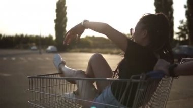 Bir otoparkta yakınındaki bir süpermarket alışveriş sepeti ile mutlu genç arkadaşlar. Adam kızın içinde ile kart bastırmak. Görüntüleri izleme