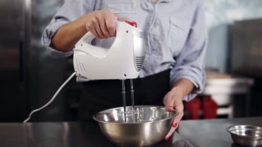 Yumurta akı çelik kase karıştırma yakın çekim. Kadın pudra çırpma için el düzenlenen Mikser kullanarak