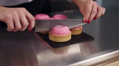 Kadının elleri pembe ayna sır ile Fransız tatlı mutfak çalışma yüzeyi kesin. Pembe kek. Görünümü kapatın