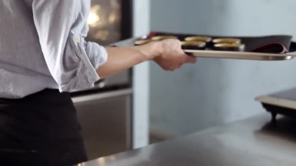 Cozinha, conceito de pastelaria. Confeiteiro pegue a bandeja com tartarugas cruas em seis formas e colocá-lo no forno. Cozinha de design moderno — Vídeo de Stock