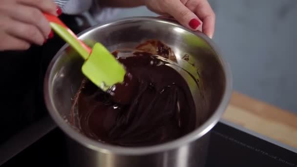 Concetto culinario, dessert. Primo piano di sciogliere il cioccolato in un bagno d'acqua in una ciotola d'acciaio, mescolando con spatola di silicone. Interni — Video Stock