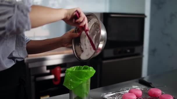 Νεαρή γυναίκα ζαχαροπλάστης βάζει κρέμα ή χτυπημένα ασπράδια στο πράσινο γαστρονομικές τσάντα από το μεταλλικό μπολ. Μοντέρνα κουζίνα — Αρχείο Βίντεο