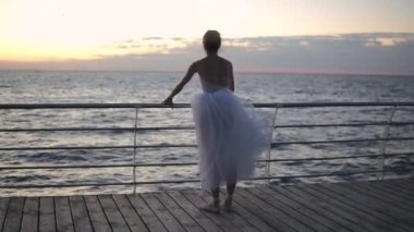 Bir balerin enine Promenade yakın duruyor. Germe, dikey bir sicim bacaklarını bükme. Çok güzel bir sabah deniz görünümü