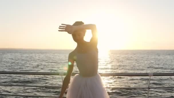 芭蕾舞演员在海边舒展, 优雅的女孩练芭蕾, 手练习。背景上的早晨太阳光线。加速镜头 — 图库视频影像
