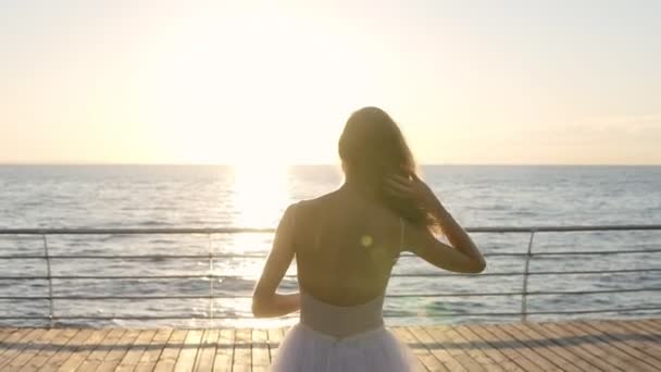 Jonge vrouw in witte ballet tutu wandelingen door embankment. Slanke meisje met lang haar heeft een rust in de buurt van de zee na de uitoefening van het ballet. Weergave achterzijde — Stockvideo