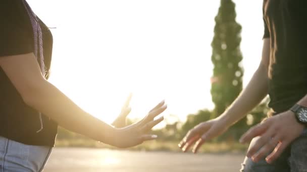 Pareja joven en la calle cogida de la mano, con camisetas de mezclilla y camisetas negras. De pie frente al sol. Primer plano de las imágenes — Vídeos de Stock