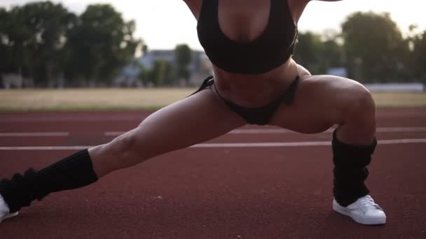 Zblízka záběry dívka natahovat nohy, kymácení ze strany na stranu. Slow motion záběry ženy sexy, svalová rozcvička venku na stadionu — Stock video