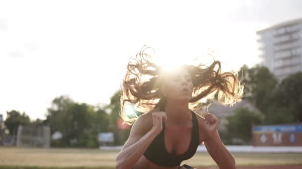 Cena linda em imagens de câmera lenta de uma mulher musculosa e apta com cabelo castanho comprido fazendo agachamentos largos ao ar livre, o sol brilha no fundo — Vídeo de Stock