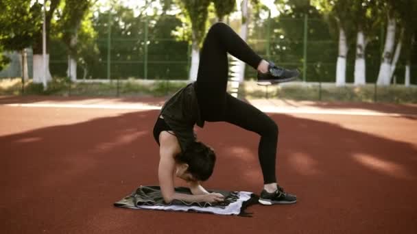 Fitness-Frau macht Bridge-Pose Yoga-Übung. von stehender Pose zur Brückenposition. Outdoor-Training im Fitnessstadion — Stockvideo