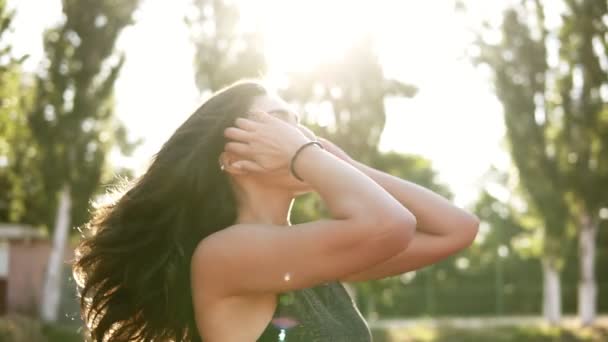 Bonita jovem mulher esporte fazendo rabo de cabelo rabo de cavalo câmera lenta. Feminino se prepara para treino de fitness ao ar livre — Vídeo de Stock