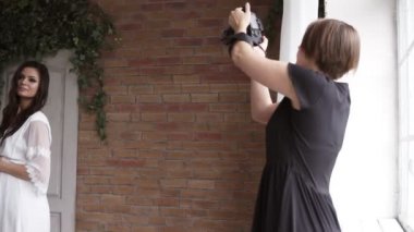 Güzel genç hamile foto model sutyen, kırmızı gömlek ve siyah pantolon kadın fotoğrafçı Sehpalar eğilerek için poz. Kapalı