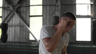 Aktif, kızgın erkek boxer eğitim süreci içinde jimnastik salonu. Görünmez bir rakiple boks, delme bir adam portresi. Arka planda windows ile eski stil spor salonu