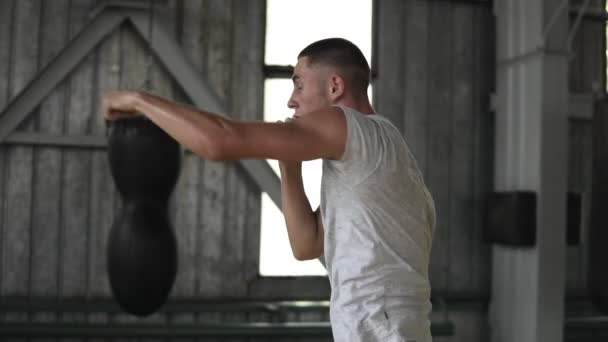 Boxer maschile pratica colpisce con un avversario invisibile, una lotta con un'ombra. Processo di allenamento in palestra di pugilato con sacchetti di vomito, finestre sullo sfondo — Video Stock