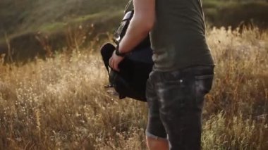 Kuru ot ile yerden sırt üstünde belgili tanımlık tepe tespit hiking genç adam. Kot gömlek ve gitmeye hazır tişörtleri giyiyor