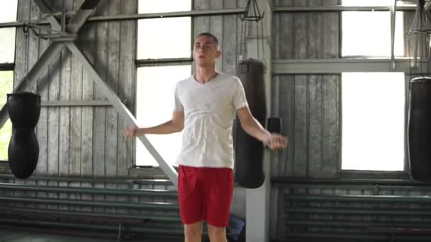 Μήκος σε πόδηα του Καυκάσου άνδρα στο λευκό T shirt και κόκκινο shirtsworking σκληρά στο γυμναστήριο πυγμαχίας. Επιμελώς άσκηση με το σχοινάκι — Αρχείο Βίντεο
