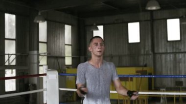Yakışıklı genç beyaz sporcu bir atlama ip ile boks spor salonunda dışarı çalışırken ip atlama ile çapraz hamle yapıyor atlıyor